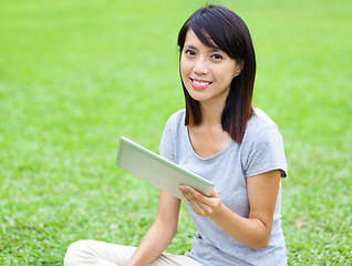 Image showing Asian woman setting on grass with tablet