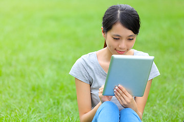 Image showing Woman setting on grass with tablet 