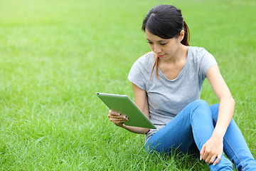 Image showing Woman sitting on grass with tablet computer