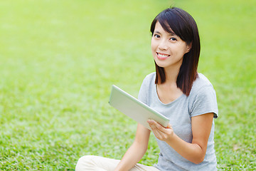 Image showing Asian woman sitting on the lawn with tablet