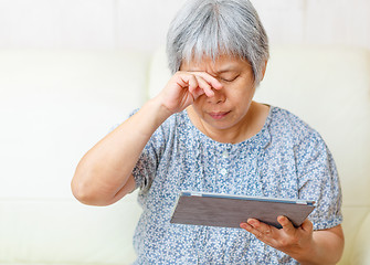 Image showing Asian old woman using digital tablet with tired eyes