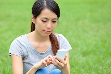 Image showing Asian woman using smartphone on grass