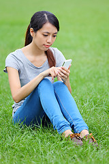 Image showing Woman sitting on grass with smartphone