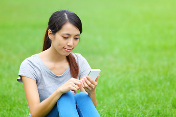 Image showing Woman sitting on grass with smartphone