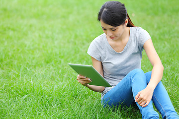 Image showing Woman sitting on grass with tablet computer