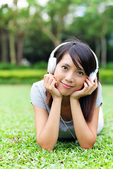 Image showing Asian woman listen to song lying on grass