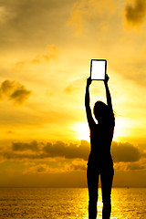 Image showing Silhouette of woman holding tablet computer at sunset