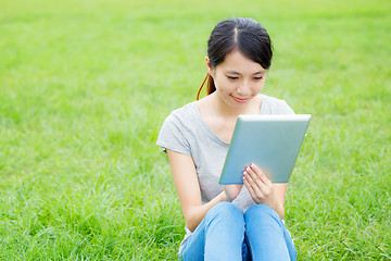 Image showing Woman sitting on grass with tablet computer