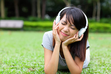 Image showing Asian woman listen to song lying on grass