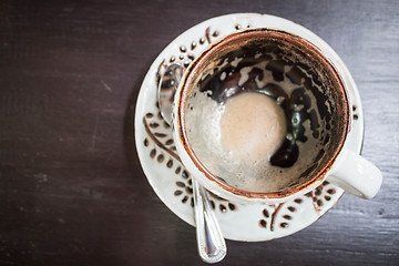Image showing Drinking out of hot cappuccino on table, view from above