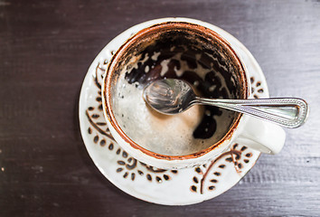 Image showing Drinking out of hot espresso cup on wooden table