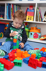 Image showing A baby boy playing with plastic blocks