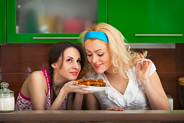 Image showing Girls try the freshly cooked homemade cookies