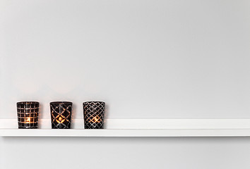 Image showing Candle lights on white shelf