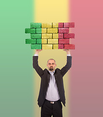 Image showing Businessman holding a large piece of a brick wall