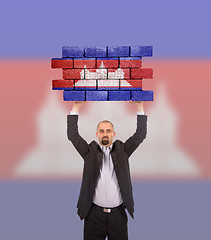 Image showing Businessman holding a large piece of a brick wall