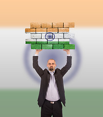 Image showing Businessman holding a large piece of a brick wall