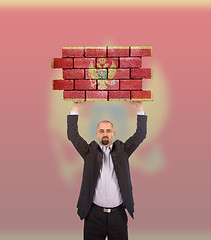 Image showing Businessman holding a large piece of a brick wall