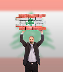 Image showing Businessman holding a large piece of a brick wall