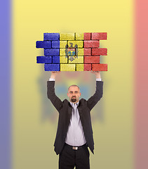 Image showing Businessman holding a large piece of a brick wall