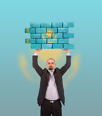 Image showing Businessman holding a large piece of a brick wall