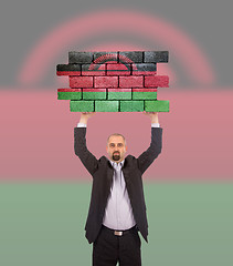 Image showing Businessman holding a large piece of a brick wall