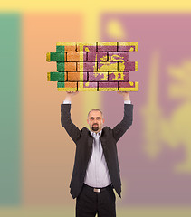 Image showing Businessman holding a large piece of a brick wall