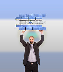 Image showing Businessman holding a large piece of a brick wall