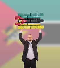 Image showing Businessman holding a large piece of a brick wall