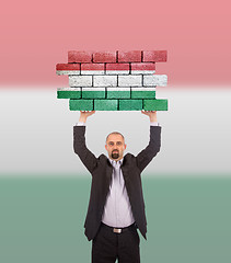 Image showing Businessman holding a large piece of a brick wall