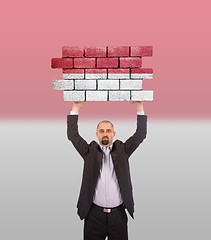 Image showing Businessman holding a large piece of a brick wall