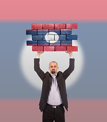 Image showing Businessman holding a large piece of a brick wall