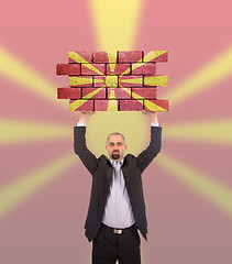 Image showing Businessman holding a large piece of a brick wall