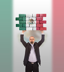 Image showing Businessman holding a large piece of a brick wall