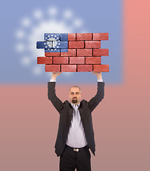 Image showing Businessman holding a large piece of a brick wall