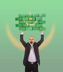 Image showing Businessman holding a large piece of a brick wall