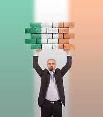 Image showing Businessman holding a large piece of a brick wall