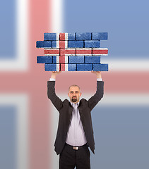 Image showing Businessman holding a large piece of a brick wall