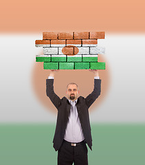 Image showing Businessman holding a large piece of a brick wall