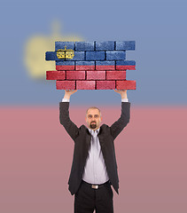 Image showing Businessman holding a large piece of a brick wall