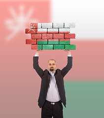 Image showing Businessman holding a large piece of a brick wall