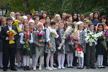 Image showing School students stand with flowers in hands on September 1.