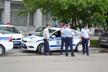 Image showing Some police officers stand at the police car