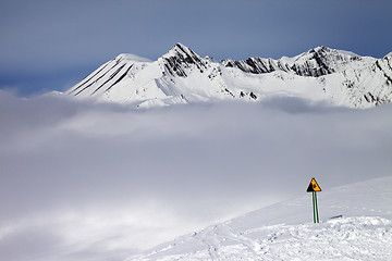 Image showing Warning sing on ski slope and mountains in fog