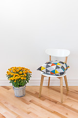 Image showing Orange chrysanthemums bright cushion on a chair