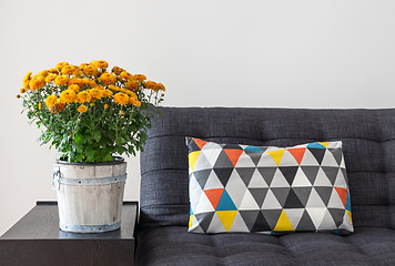 Image showing Orange chrysanthemums and bright cushion on a sofa 
