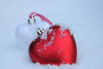 Image showing Red and white heart ornaments in snow