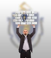 Image showing Businessman holding a large piece of a brick wall