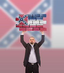 Image showing Businessman holding a large piece of a brick wall