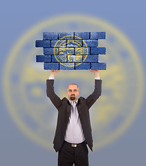 Image showing Businessman holding a large piece of a brick wall